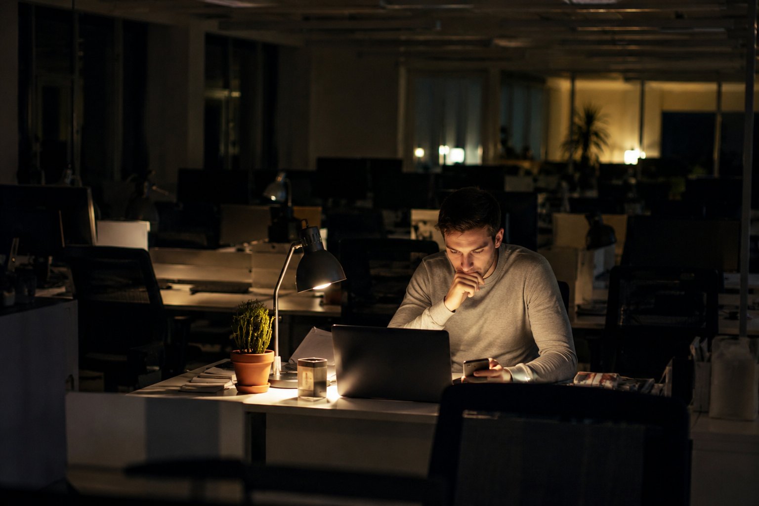 A single lit desk in an open-plan office after hours